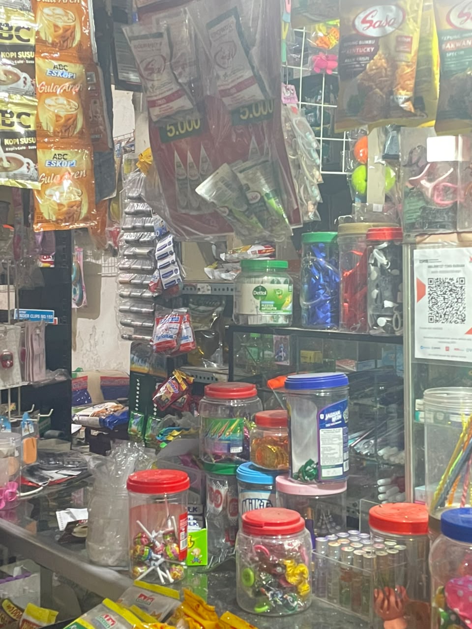 Etalase toko dengan toples permen dan aneka produk sachet